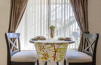 a dining table with two chairs in front of a window