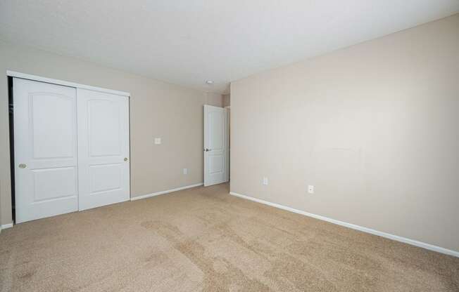 a spacious living room with carpet and white doors