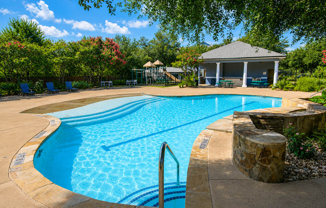 A large swimming pool surrounded by trees and a gazebo.
