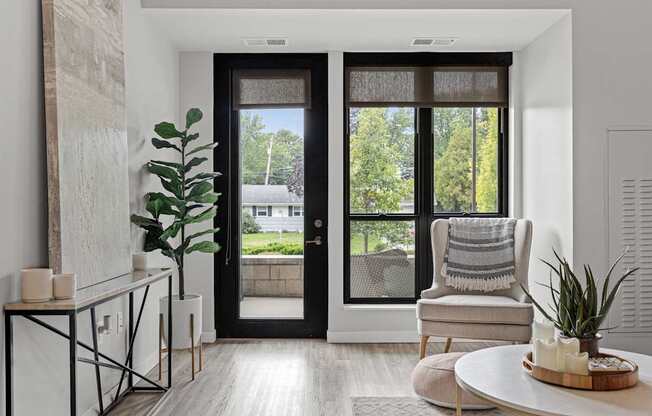 A modern living room with a black door and a view of a green lawn outside.