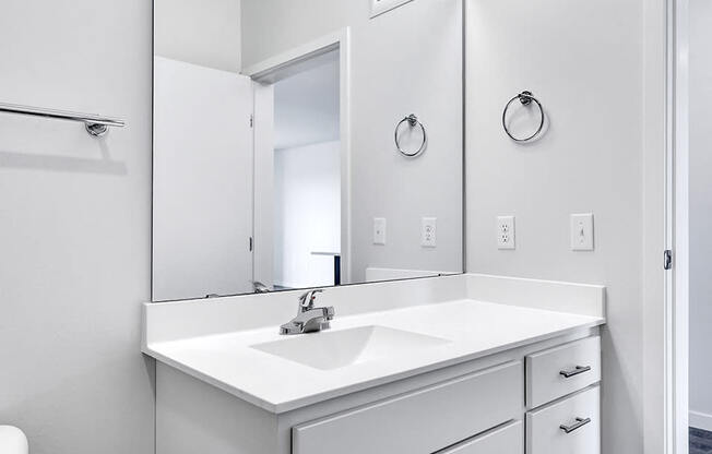bathroom sink and mirror with white countertop, walls, and shelves