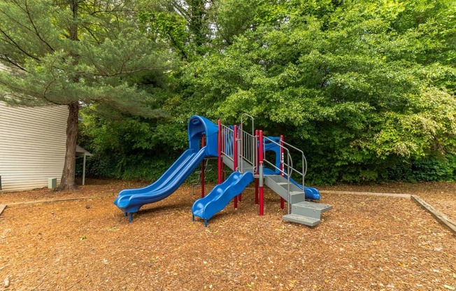 A playground with a blue slide and red railings.