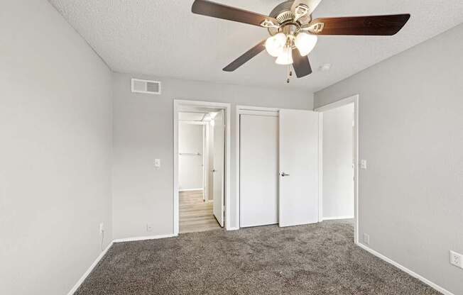 A room with a ceiling fan and carpeted floor.