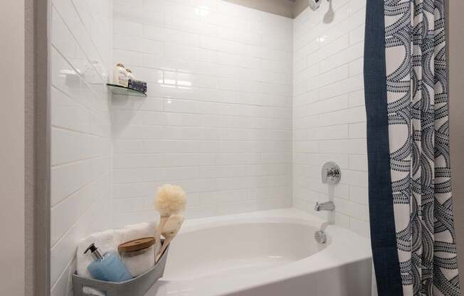 A white bathtub with a shower curtain and a shelf above it.