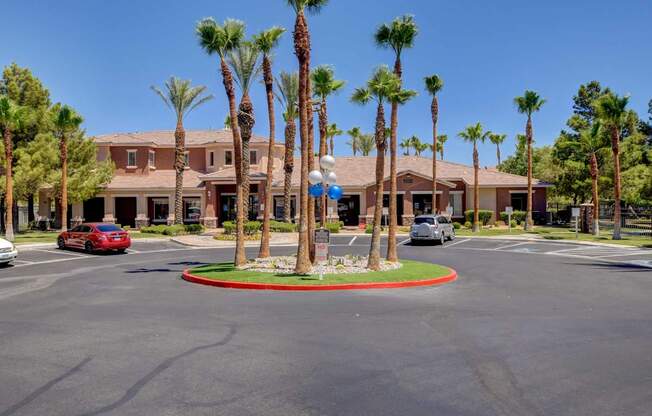 A roundabout with a sign in the middle of it and palm trees around it.