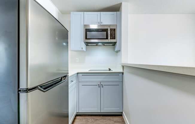 a kitchen with white cabinets and a stainless steel refrigerator