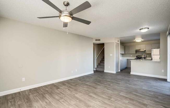 A room with a ceiling fan and light fixture, and a kitchen area in the background at Sterling Point Apartment Homes, Phoenix