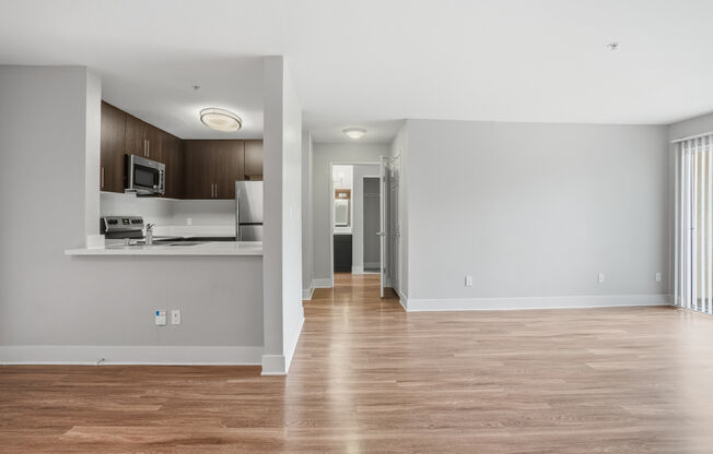A spacious living room with a kitchen area in the background.