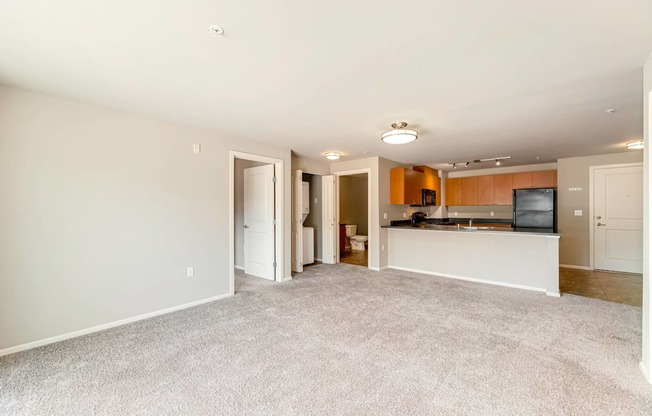A spacious living room with a television and a kitchenette in the background.