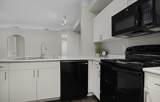 an empty kitchen with black appliances and white cabinets