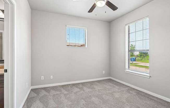 A room with a ceiling fan and a window with blinds.