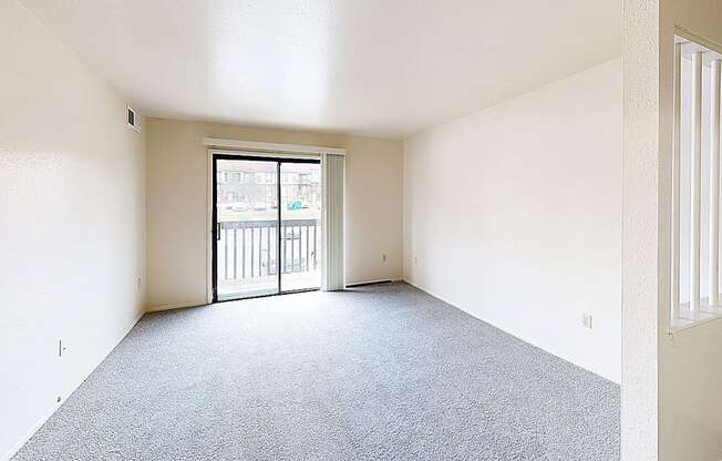 an empty living room with a door to a balcony