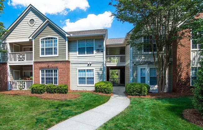 Meticulously maintained grounds with mature trees surround the soft green paint and brick exterior apartment homes at Autumn Park Apartments, Charlotte, NC 28262