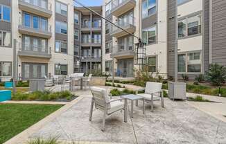 an outdoor patio courtyard with tables and chairs in front of an apartment building at LynnCora, Grand Prairie