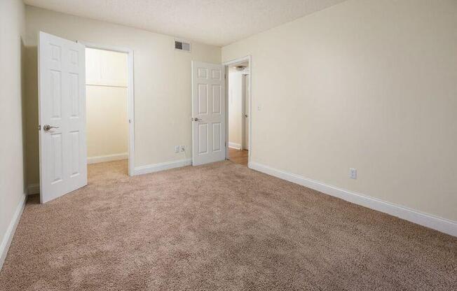 an empty room with a carpeted floor and two doors