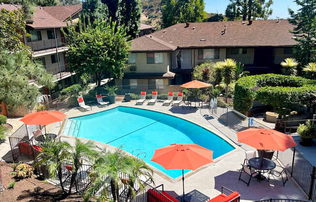 a swimming pool with umbrellas in front of a house