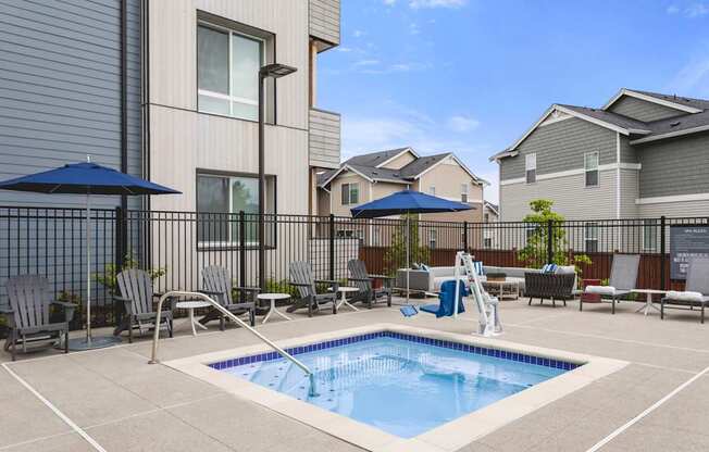 A small pool in a backyard surrounded by chairs and umbrellas.