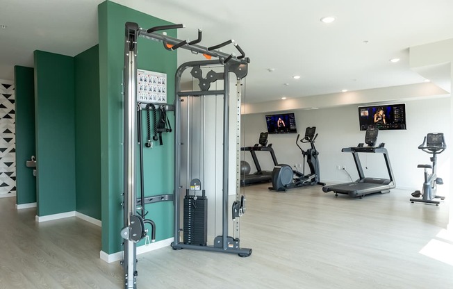 A gym with a variety of equipment including treadmills, stationary bikes, and weight machines.