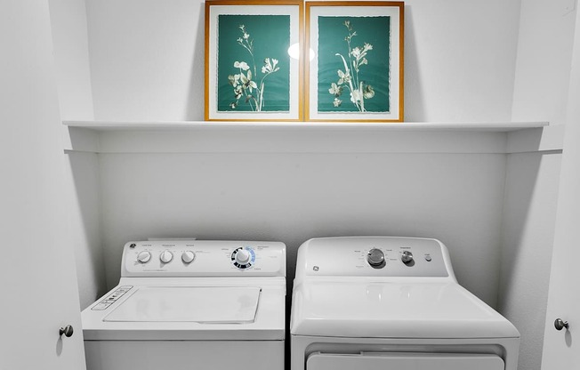 Two white front load washing machines in a laundry room.