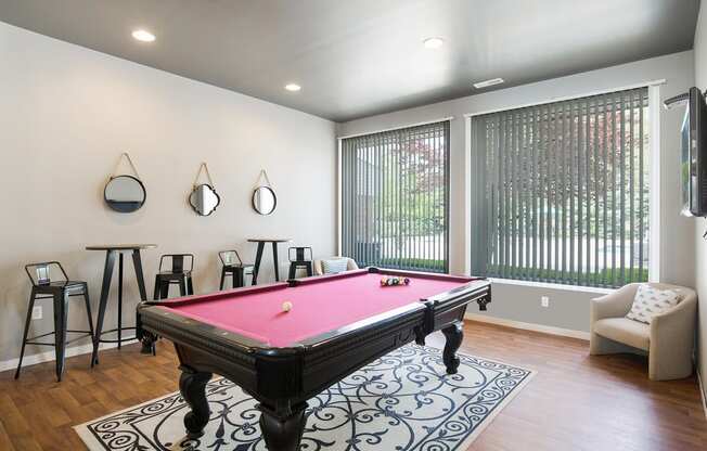 a game room with a pink pool table and bar stools