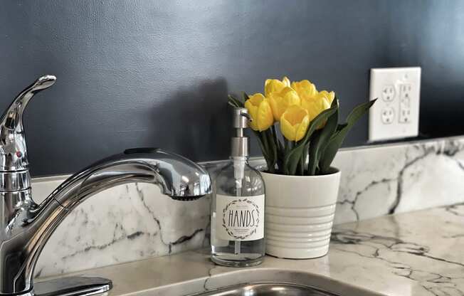 a kitchen sink with a vase of yellow flowers next to it