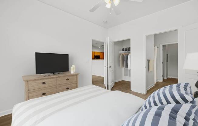 A bedroom with a bed, dresser, and a television.
