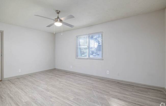 A room with a ceiling fan and a window with blinds.
