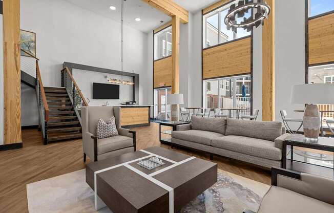 A modern living room with a staircase and a kitchen area in the background.