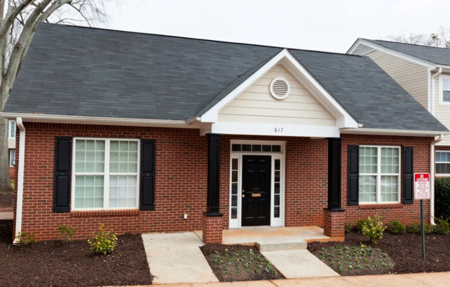 a small brick house with black shutters and a black front door