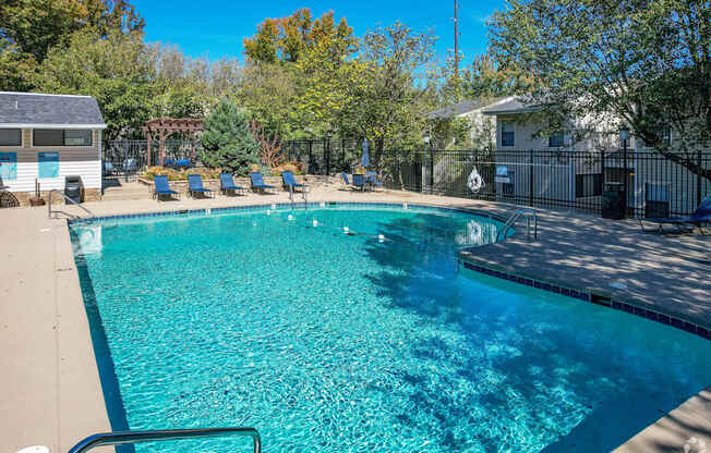 A swimming pool surrounded by trees and a fence.