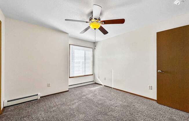 an empty room with a ceiling fan and a window