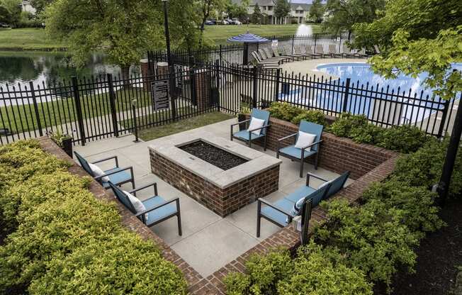 a patio with a fire pit and chairs next to a pool
