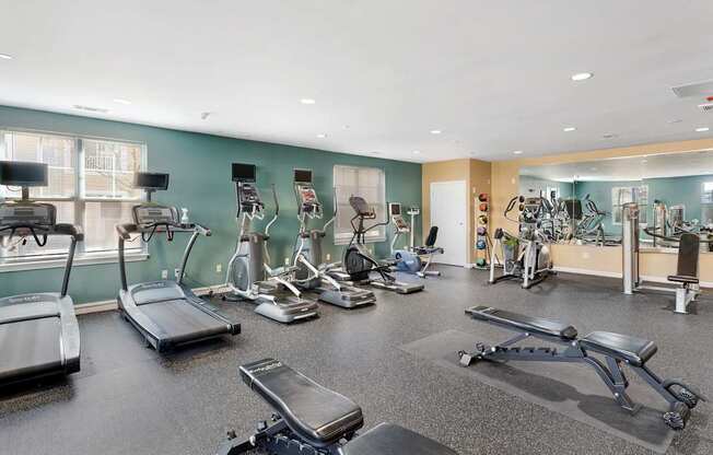 A gym with treadmills, exercise bikes, and other equipment at Parkside Commons