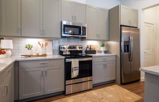 A kitchen with a refrigerator, microwave, and oven.