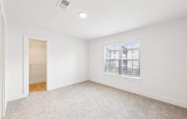 A bedroom with a window and a carpeted floor.