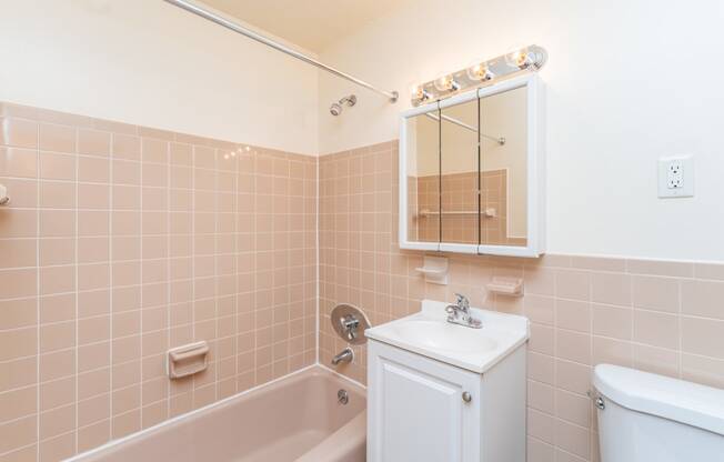 a bathroom with peach tiles and a white sink and bathtub