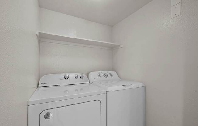 Two white washing machines in a small laundry room.