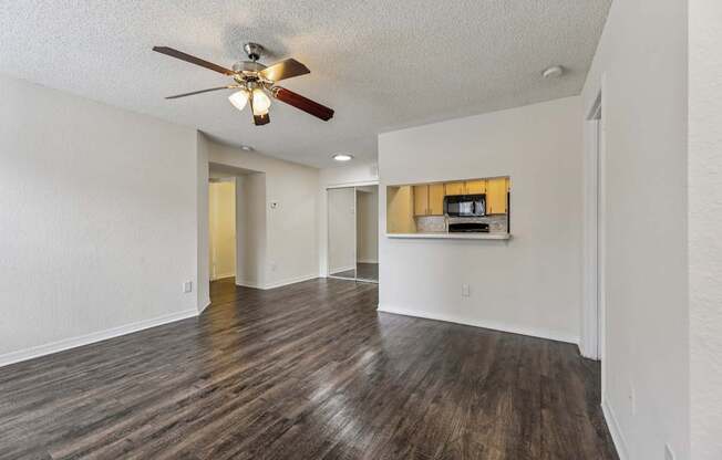 A room with a ceiling fan and wooden flooring.