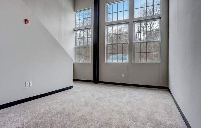 an empty room with three windows and a carpeted floor