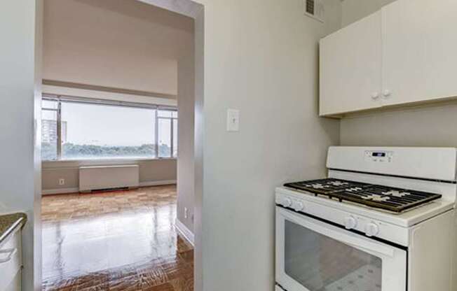 A white stove in a kitchen with a window overlooking a balcony.