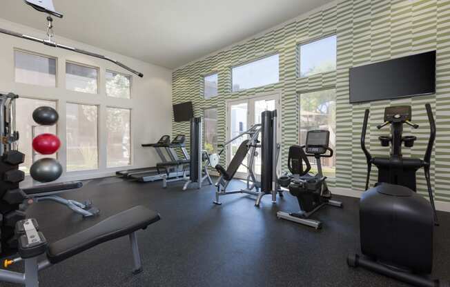 the gym has plenty of exercise equipment and windows