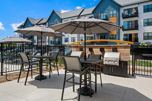 a patio with tables with umbrellas and chairs and a grill