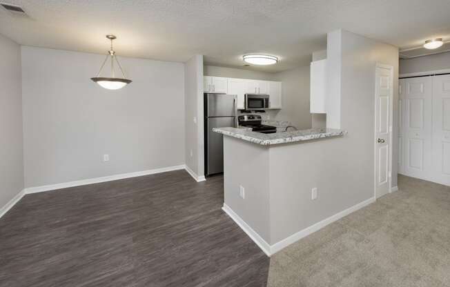 an empty living room and kitchen with a counter top and a refrigerator