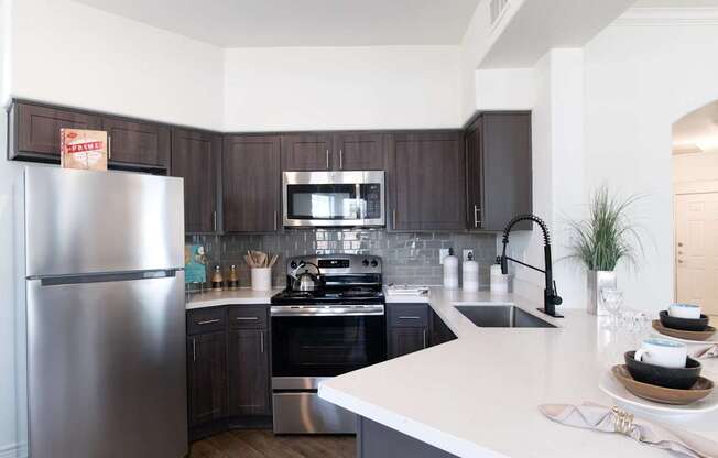 A kitchen with a refrigerator, oven, and sink.