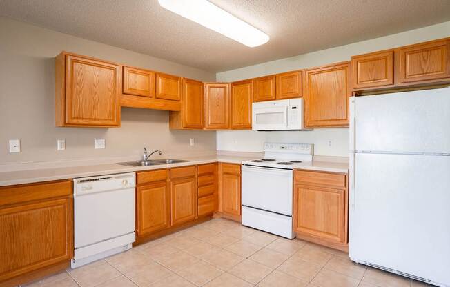 A kitchen with wooden cabinets and white appliances. Fargo, ND Stonebridge Apartments