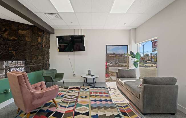 A living room with a stone wall and a flat screen TV mounted on the wall.