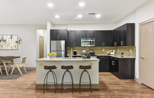 a kitchen with black cabinets and a counter with three stools