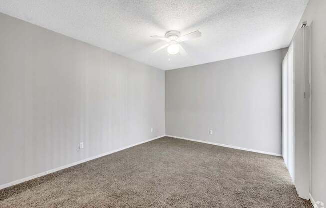 A room with a carpeted floor and a ceiling fan.