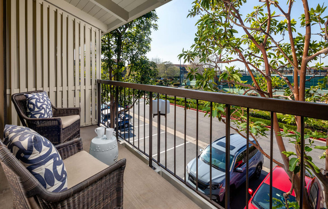 a balcony with two chairs and a view of a parking lot