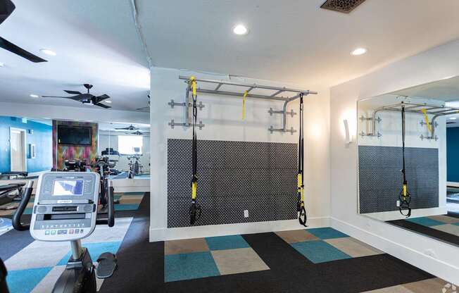 A gym with a treadmill, a wall-mounted mirror, and a wall-mounted pull-up bar.